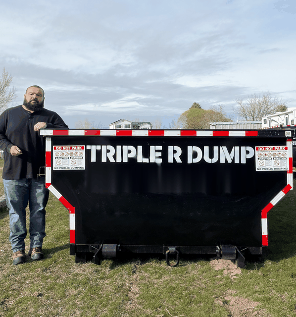 Joseph Rodrigues standing beside a 15 yard Triple R Dump roll-off bin